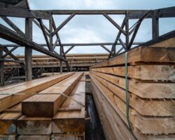 Stacked reclaimed timber beams beneath an exposed wooden roof frame