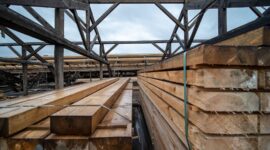 Stacked reclaimed timber beams beneath an exposed wooden roof frame