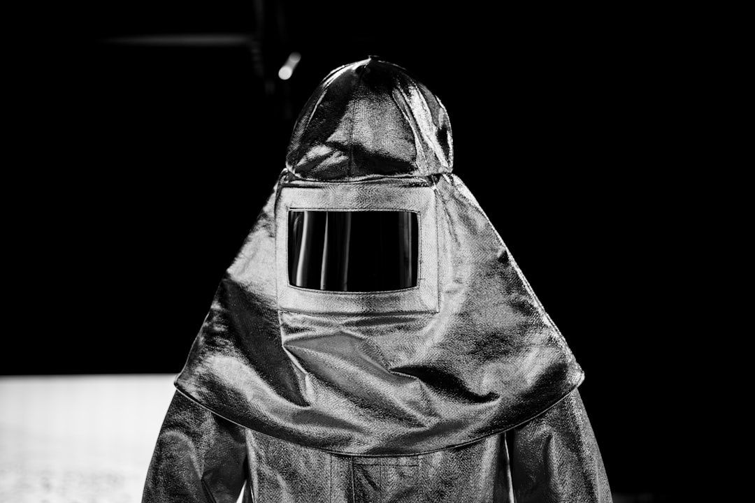 Black-and-white image of a worker in a full protective suit and visor