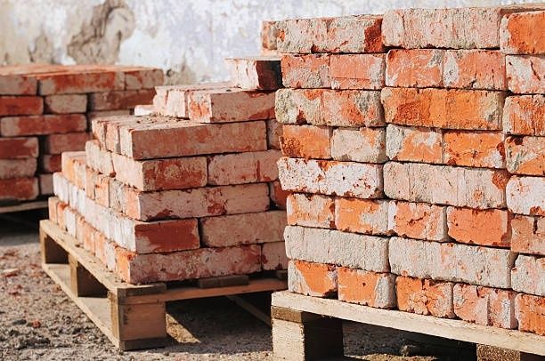Stacks of weathered reclaimed bricks arranged on wooden pallets